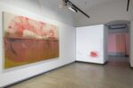 Foto eines Ausstellungsraum mit abstrakter Malerei. Man erkennt zwei Werke. Das hintere Werk dient als Projektionsleinwand.