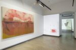 Foto eines Ausstellungsraum mit abstrakter Malerei. Man erkennt zwei Werke. Das hintere Werk dient als Projektionsleinwand.