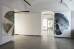 Foto eines Ausstellungsraumes mit abstrakter Malerei. Die Malereien zeigen Halbkreise. Im Hintergrund sind zwei weitere Ausstellungsräume mit abstrakter Malerei und Videoprojektion zu erkennen.