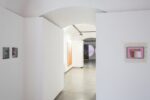 Foto eines Ausstellungsraum mit abstrakter Malerei.. Im Hintergrund erkennt man einen weiteren Ausstellungsraum mit einer Malerei an der Stirnwand, die von einer Projektion überlagert wird.