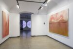 Foto eines Ausstellungsraumes mit zwei abstrakten Malereien. Die Malereien zeigen Halbkreise. Die Malerei an der Stirnwand wird von einer Projektion überlagert.