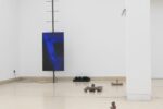 Photo of exhibition space with monitor on steel object and objects on the floor