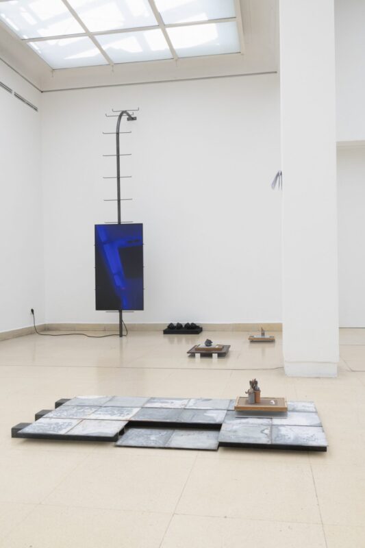 Photo of exhibition space with monitor on steel object and objects on the floor