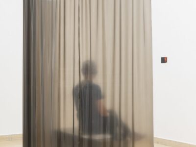 Aussstellungsraum mit Latexvorhang und dahinter Person mit Kopfhörer