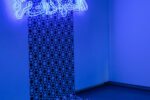 blue neon light in arabic letters saying "Once we were brothers" in front of a modern grafic wallpaper