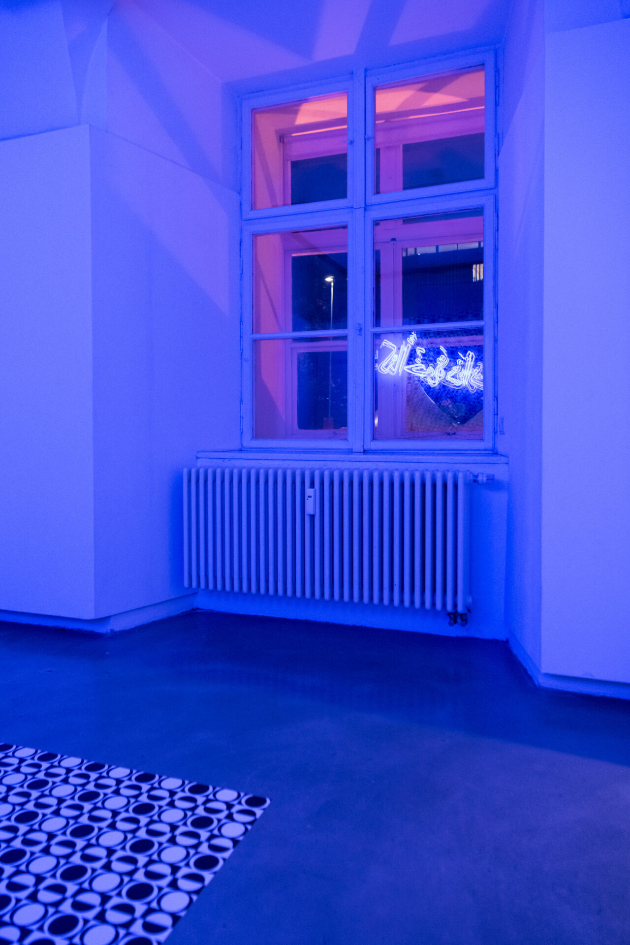 eine Spiegelung der Neonschrift "Once We Were Brothers" im Fenster der Galerie