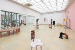 Exhibition view Kunstpavillon with wooden sculptures painted in different colours, in various sizes and heights, with photographs