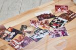 Fotos auf einem Holztisch darüber liegt ein kurvig ausgeschnittenes Plexiglas Objekt