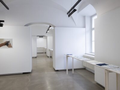 Foto Ausstellung Neue Galerie mit schmalen Tischen und weißen, blauweißen und blauen Blättern darauf