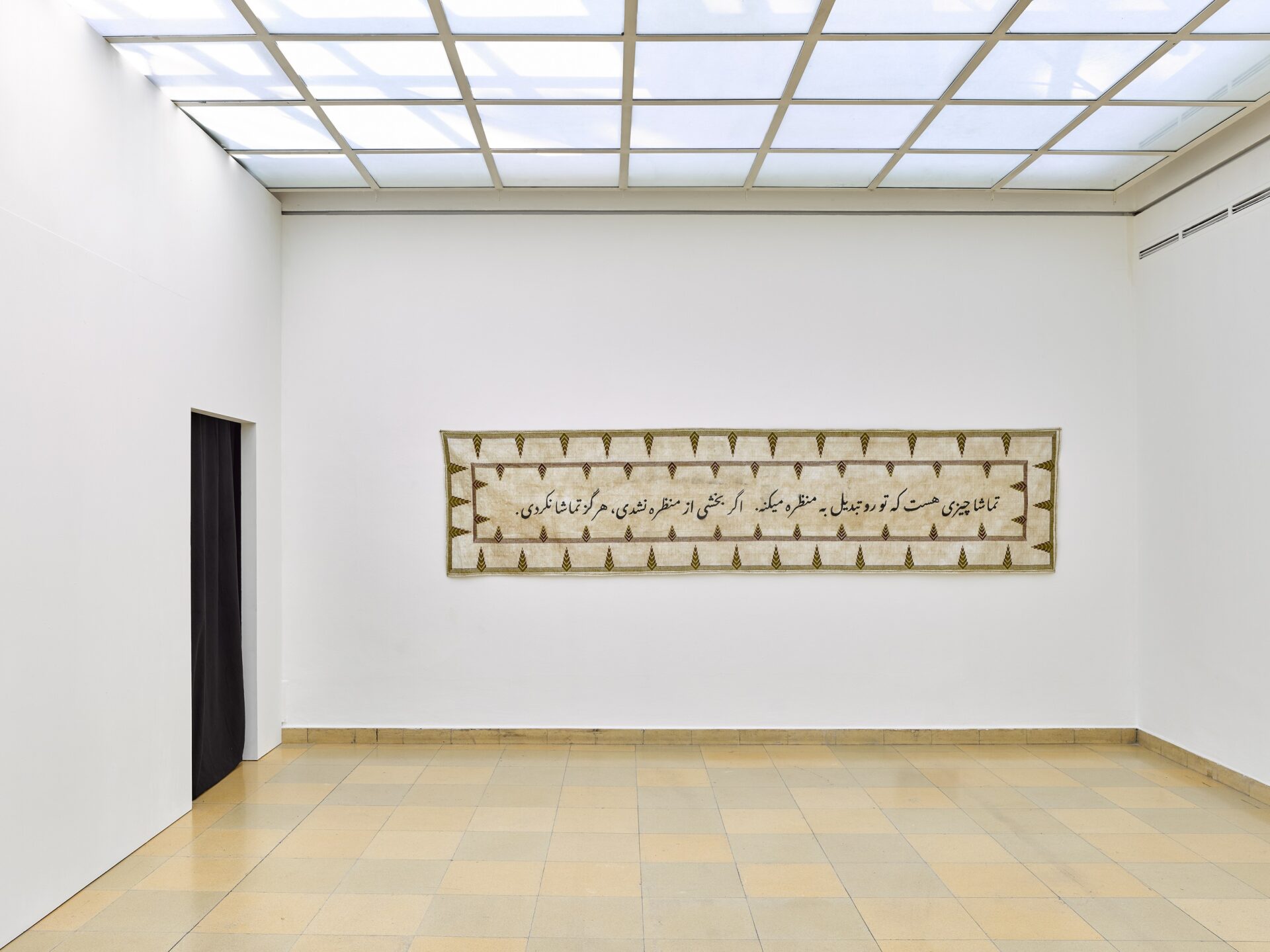 Foto aus Ausstellung mit besticktem Banner und arabischer Schrift