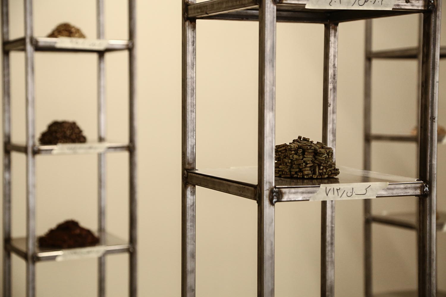 Photo exhibition with metal shelves; dark brown cores lie in piles on the metal floors.