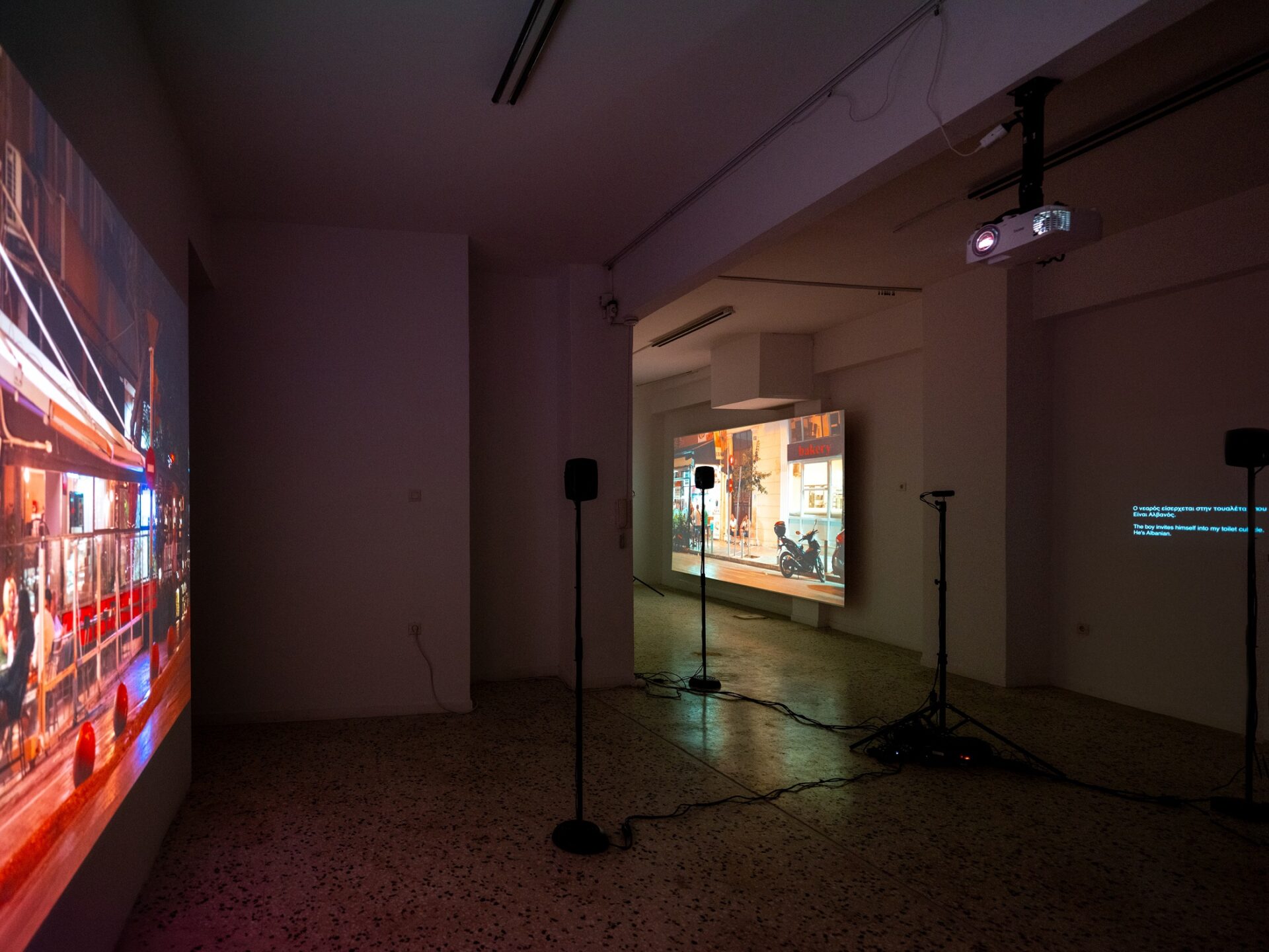 Foto Ausstellung mit zwei farbign Projektionen mit Menschen in einem Cafe an der Straße