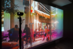 Photo exhibition with colorful projection of people sitting in a cafe next to the street