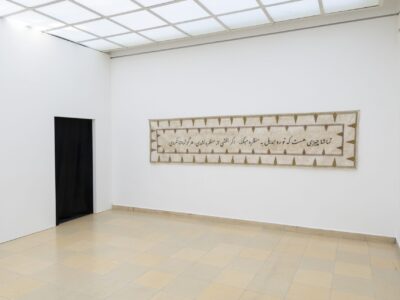 Foto aus Ausstellung mit beticktem Banner und arabischer Schrift