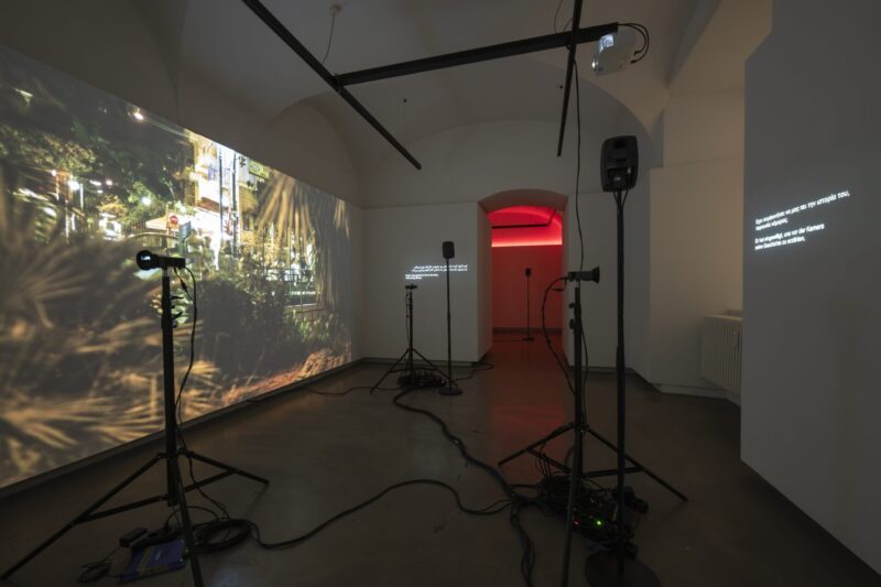 Photo exhibition with video and text on the wall, red light in the back room