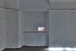 Photo of an exhibition featuring coloured pencil lines on white paper drawings on white paper rolls, and a small light box with drawings on the right