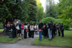 Documentation photo of the performance with a women sitting on a table in a garden surrounded by people