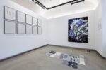 Foto Ausstellungraum mit gerahmten schwarz weiß Bildern links, Foto Blumenstrauß vor schwarzem Hintergrund und Assemblage am Boden