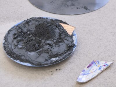 Foto Ausstellung Assemblage am Boden runder Kreis mit schwarzem Pulver darauf