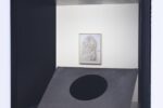 Ausstellungsansicht Blick durch Fenster in Galerieraum, glänzender Kreis auf beigem Filz und Sand, Bild an der Wand im Hintergrund
