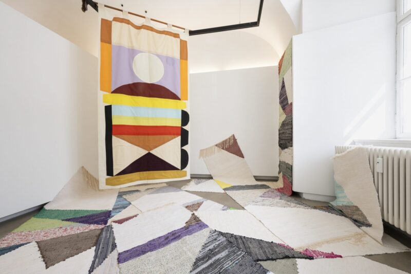 Exhbition view mit carpets and colorful banner